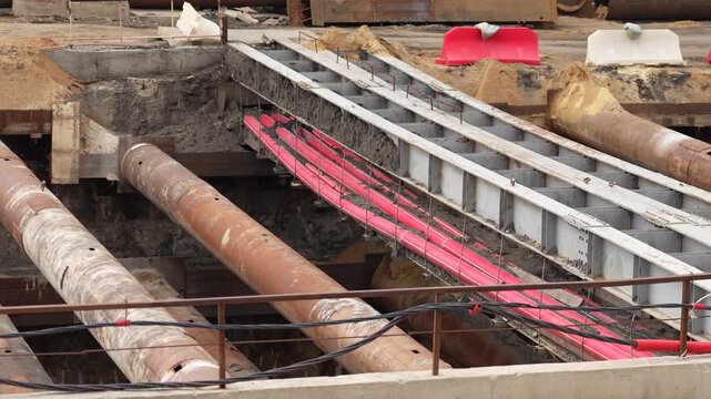 Concrete excavation structure with steel supports and temporary metal framework at a metro construction site, illustrating underground railway engineering and urban infrastructure development