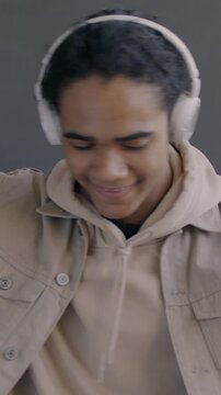Slow motion portrait of happy African American man listening to music with headphones dancing on black color background. People and entertainment concept.