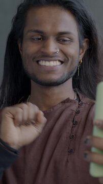Joyful Indian man making online video call with smartphone talking laughing on black color background. People and virtual meeting concept.