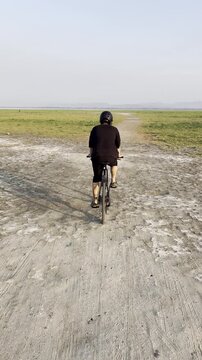 Person Riding Bicycle on Dirt Path