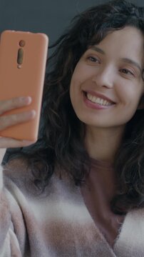 Joyful Middle Eastern woman making online video call with smartphone chatting on black background. People and communication concept.