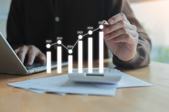 businessman write virtual strategy of business profit statistic graph for new year 2027 target and financial forecasting in office room concept