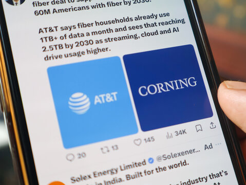 Mobile phone screen displaying AT&T and Corning logos for fiber optic network news.