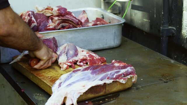 Close-up chef cutting raw meat on board for pilaf