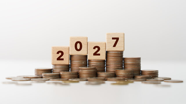 Stacks of coins with wooden blocks forming number 2027 for target financial growth, investment planning, money savings to wealth, business goals concept. Budget and tax, Happy new year 2027