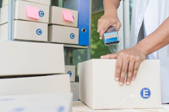 Close-up view hands of person using tape closing parcel box