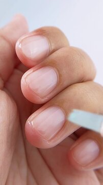 Applying clear liquid on nails for glossy shine. Close up of healthy protected nails, manicure nail care treatment for beauty, and daily nail health.