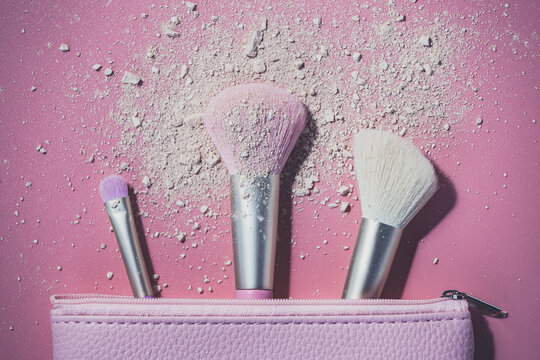 Make up brushes with powder on pink background