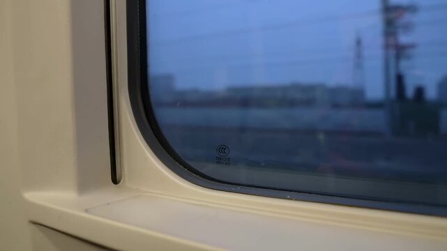 Blurred dusk city view through a train window from inside a moving carriage