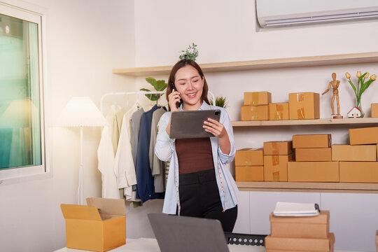 Asian small business owner on phone call using tablet for e-commerce order management