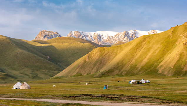 Traditional yurts beneath snowcapped Kakshaal Too mountains in Kok Kiya Valley near Kel Suu, Kyrgyzstan