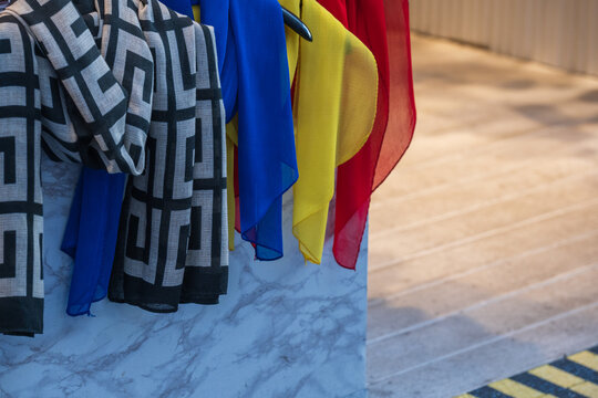 Colorful fashion scarves and patterned shawls hanging for sale at an outdoor traditional market stall in South Korea.