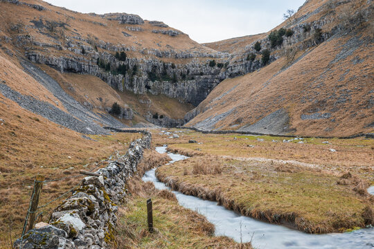 Gordale Scar, a dramatic limestone ravine with towering overhanging cliffs and Gordale Beck flowing through it in North Yorkshire, England