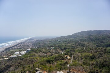 Obraz premium A panoramic view of Java's southern coast and the crashing waves of Parangtritis Beach, captured from the top of the Obelix cliff.