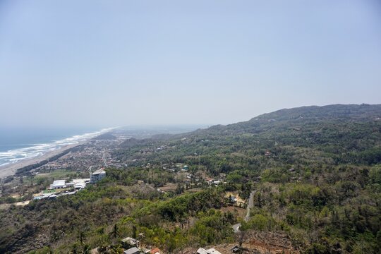 A panoramic view of Java's southern coast and the crashing waves of Parangtritis Beach, captured from the top of the Obelix cliff.