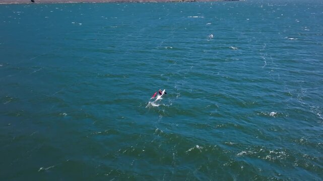 An aerial drone view circling a lone paddler in a canoe with an outrigger competing in a prestigious race in the Columbia River Gorge with heavy waves and beautiful rugged shorelines