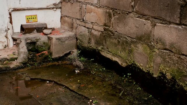 Weathered Stone Wall with Moss and Water Drain in Rustic Outdoor Setting