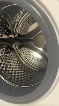 Vertical close up view of clean empty metallic drum of modern automatic washing machine with open door before loading clothes in bathroom. High quality 4k footage
