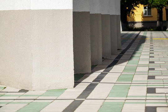 Minimalist concrete columns standing in row on decorative tiled pedestrian walkway on sunny afternoon with copy space