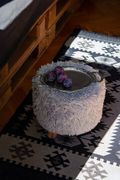 Serbian home interior detail with knit kilim rug and a foot stool with plums on a tray