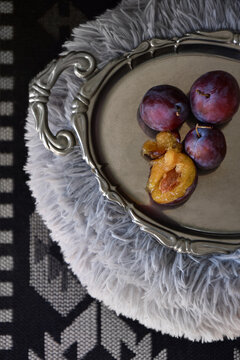 Fresh ripe plums on a decorative silver tray closeup top view