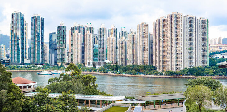 High-density residential buildings along a waterfront surrounded by greenery in Hong Kong, showing urban living and sustainable city development.