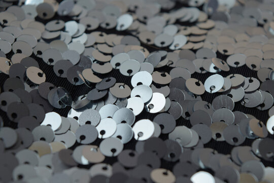 Close-up of silver sequins on fabric, glittering texture with bokeh effect