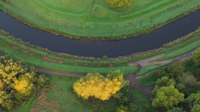Aerial video capturing the blue River Mersey meandering past Didsbury Golf Course fairways, Stenner Woods, and dewy Millgate Fields at sunrise.
