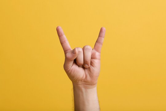 The Hand Horns Rock Gesture in Bright Yellow Studio Lighting