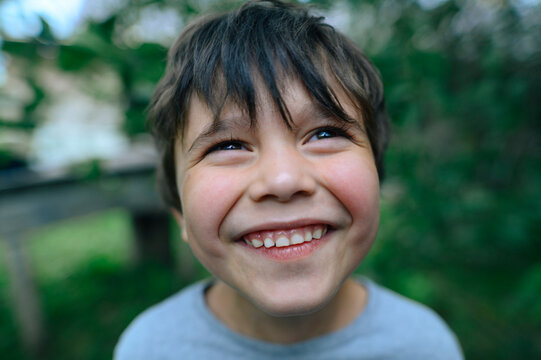 A happy boy smiles outside during summer