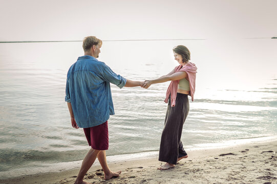 A loving couple holds hands while walking on the summer beach