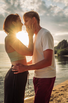 A happy man and woman embrace each other on the beach at sunset