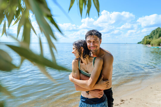 A happy couple embraces on a sunny beach during their summer vacation