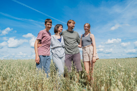 A happy family embraces each other in a sunny summer field