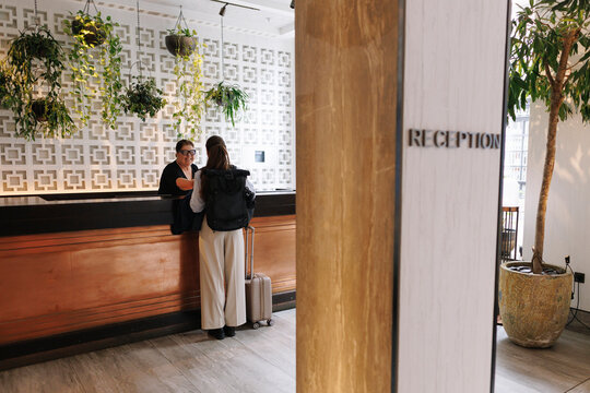 Woman with luggage checks in at the hotel reception desk