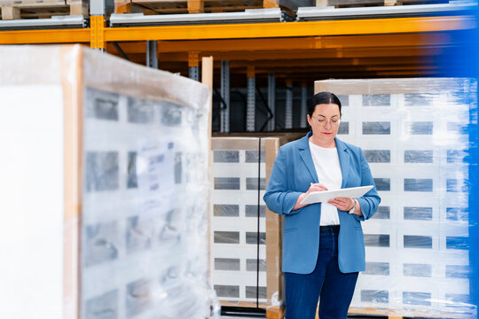 Businesswoman checks inventory on a tablet in a warehouse