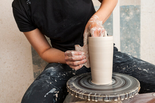 Artisan shaping a clay vase on a pottery wheel in a studio