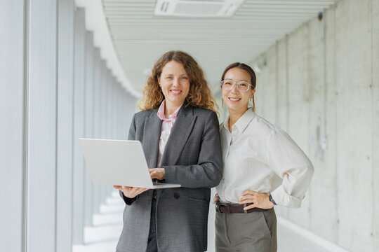 A businesswoman holds a laptop next to her colleague in the office