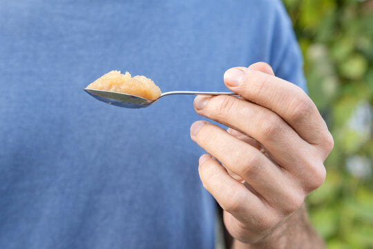Hand holding a spoonful of homemade fruit puree - applesauce - , close up emphasizing fresh, natural sweetness and healthy eating for breakfast, snack or dessert
