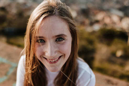 Smiling girl looks at the camera outdoors