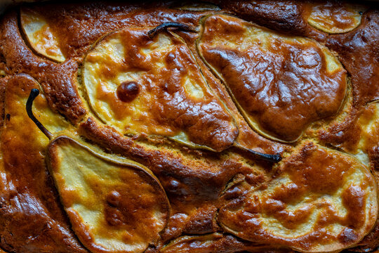 Closeup texture of homemade pear pie. Top down view of delicious freshly baked pear cake texture with caramelized golden brown crust and whole sliced fruits embedded in the dough