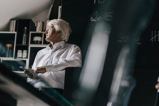 Senior businessman with smartphone in the kitchen