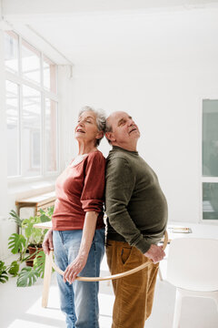 A man and a woman hold a hula hoop together indoor