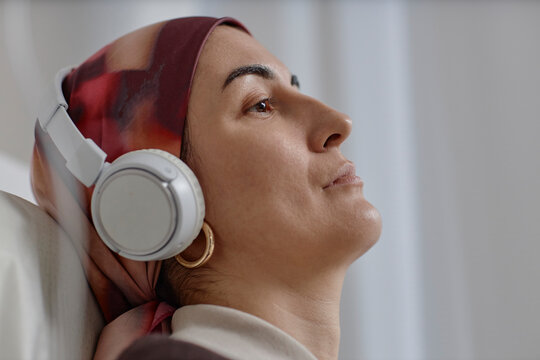 Adult wearing headscarf and headphones listening to music indoors