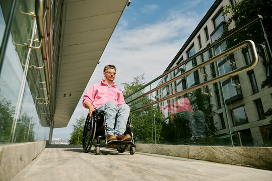 Man in a wheelchair navigates a modern urban ramp