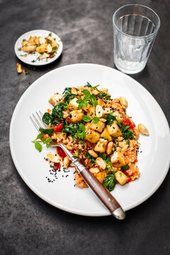 A white plate serves vegan pearl barley risotto with crispy tofu