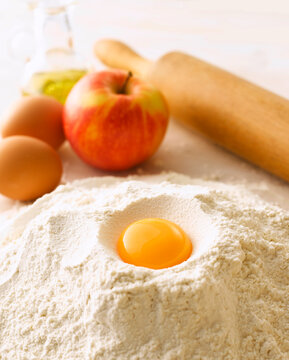 Raw egg yolk sits in a pile of flour for baking preparation