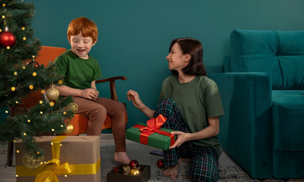 Mother giving a Christmas gift to her smiling son at home