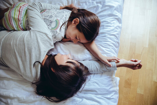 Mother and daughter cuddling on bed