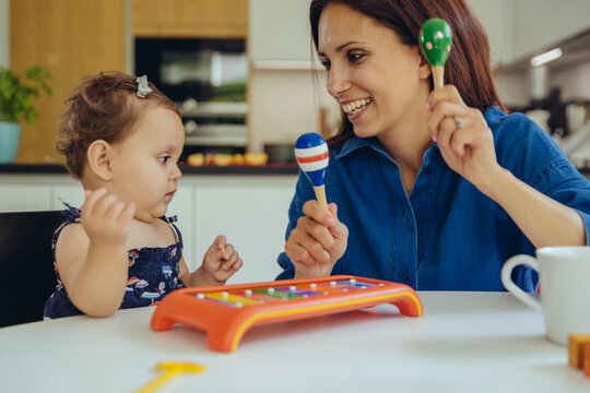 Happy mother and baby daughter playing with rattles